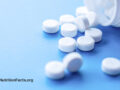 White tablets from a bottle onto blue surface